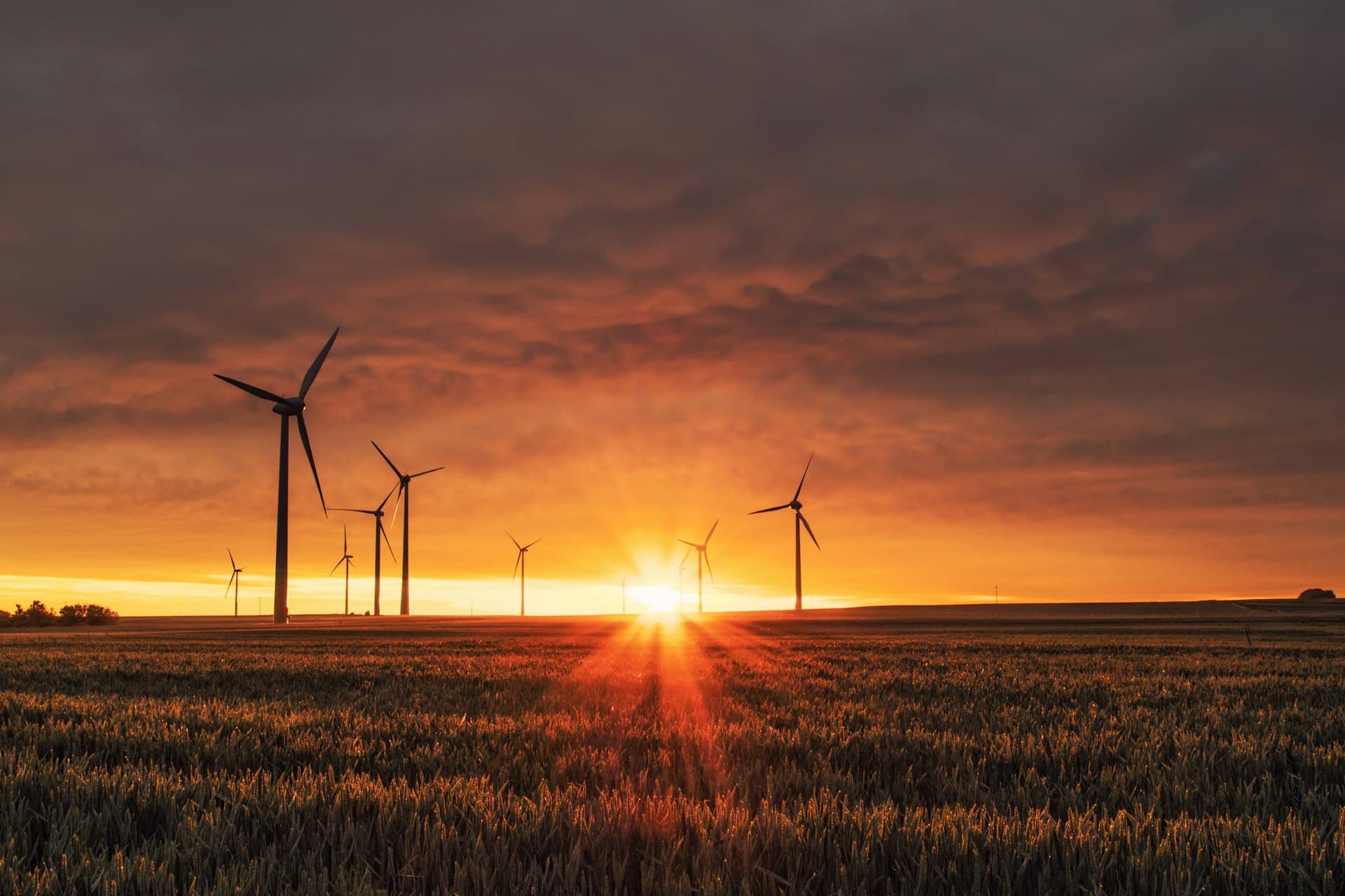Close-up of a wind turbine over green fields at sunset